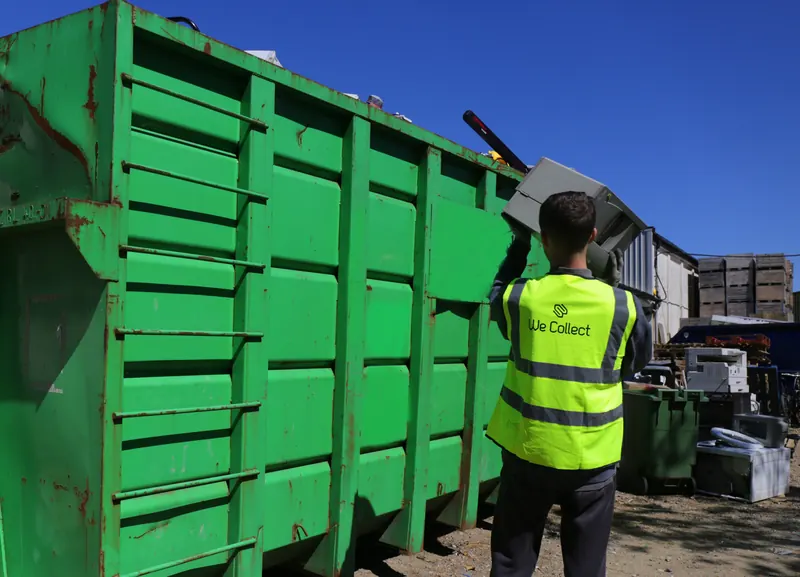 We Collect team member loading electrical waste into a branded green skip